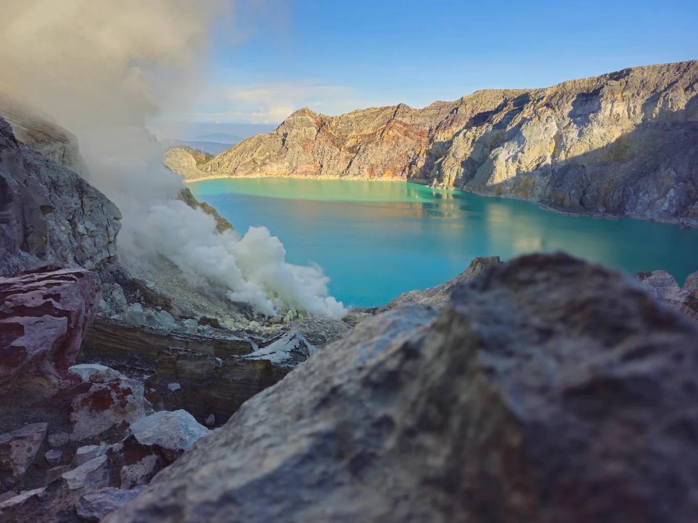 Turquoise crater lake and sulphur smoke at Ijen